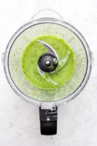 a food processor filled with green sauce.