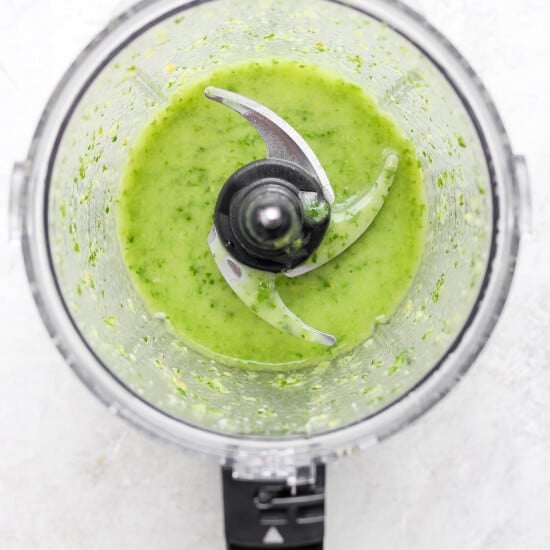 a food processor filled with green sauce.