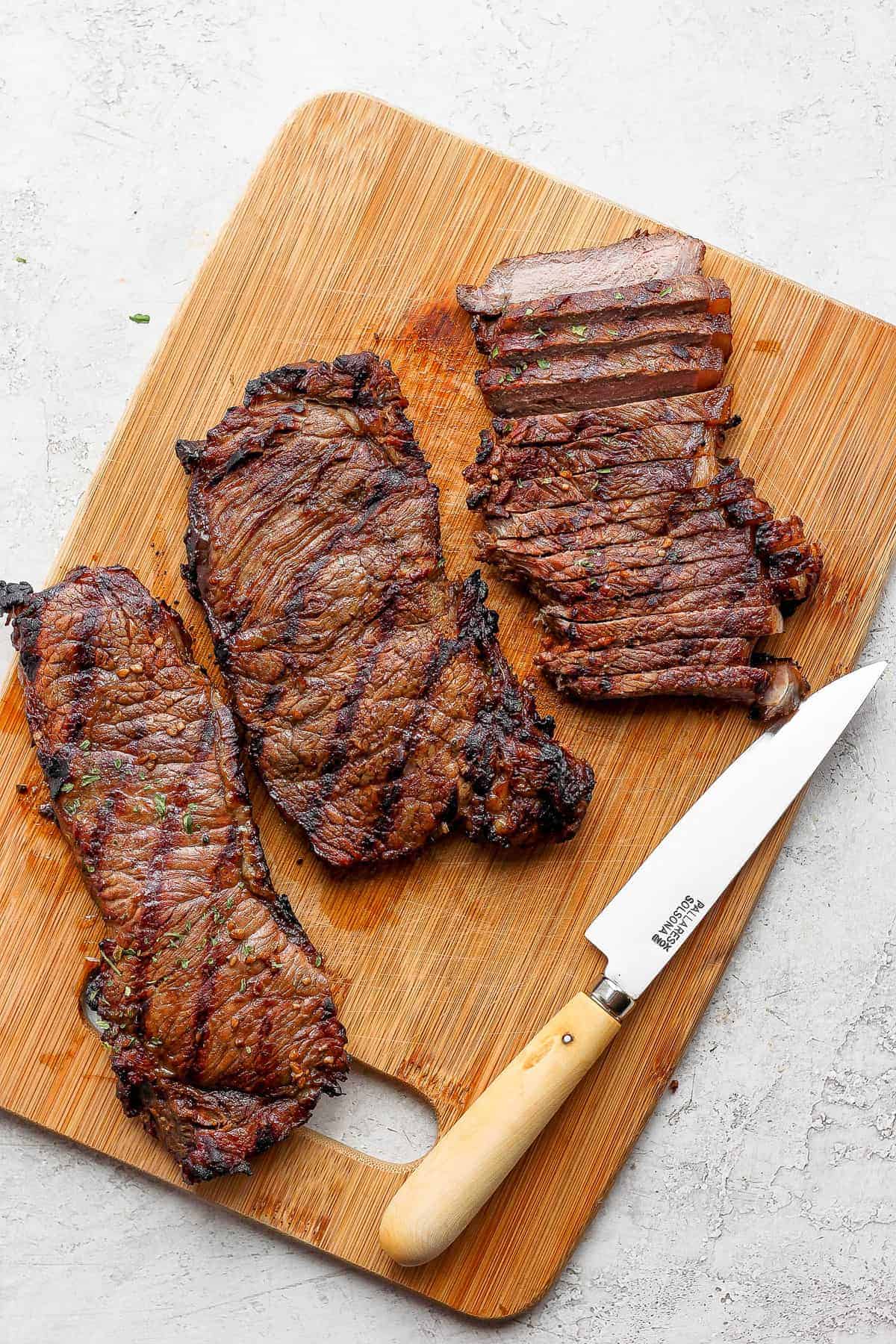 sliced cooked steak on cutting board.