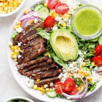 a salad with steak, corn, avocado and guacamole.