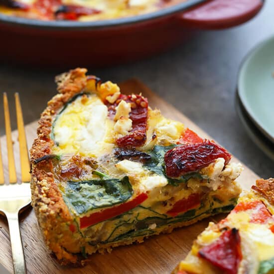 a slice of quiche on a cutting board with a fork.