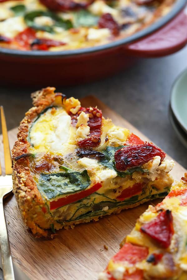 a slice of quiche on a cutting board with a fork.