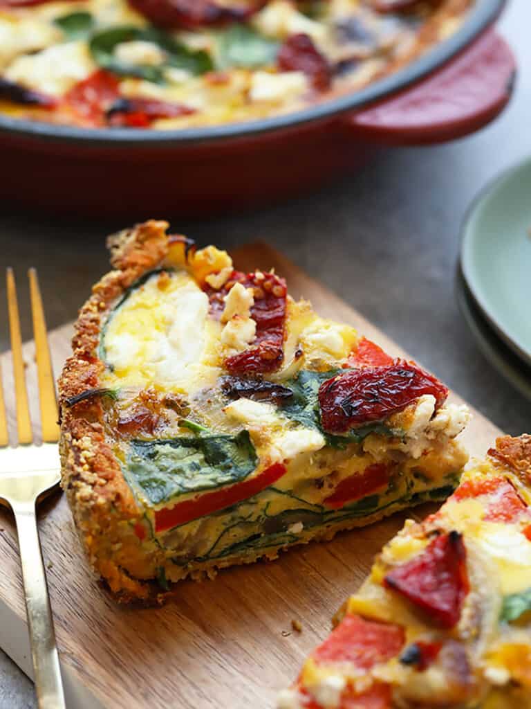 a slice of quiche on a cutting board with a fork.