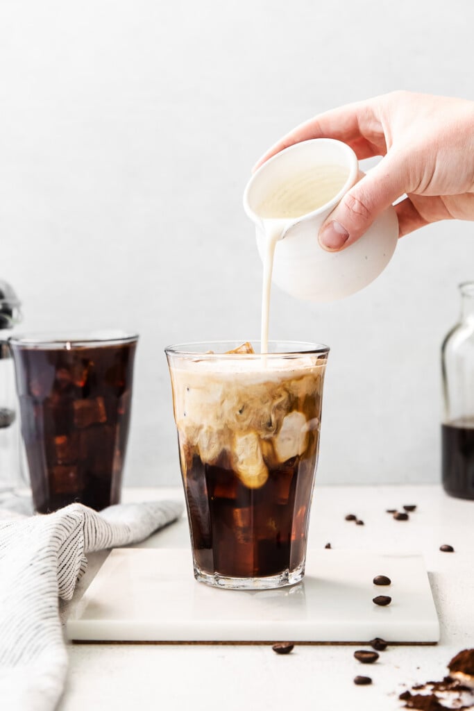 Pouring cream into cold brew coffee