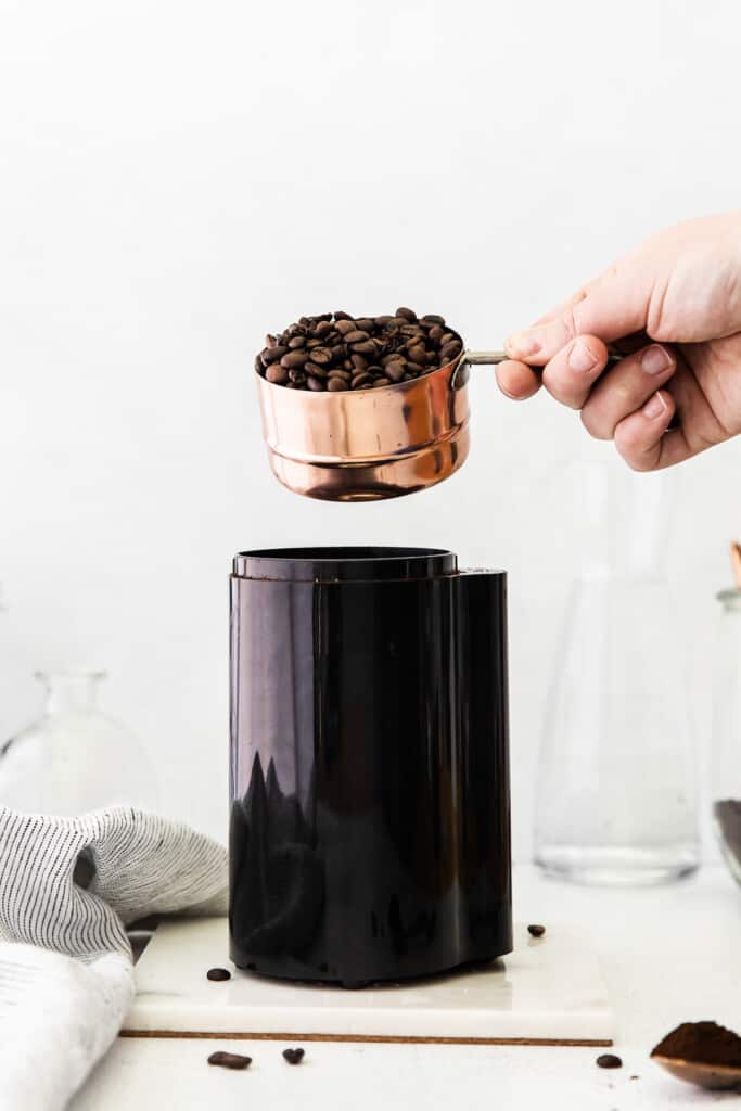 Pouring coffee beans into a coffee grinder.
