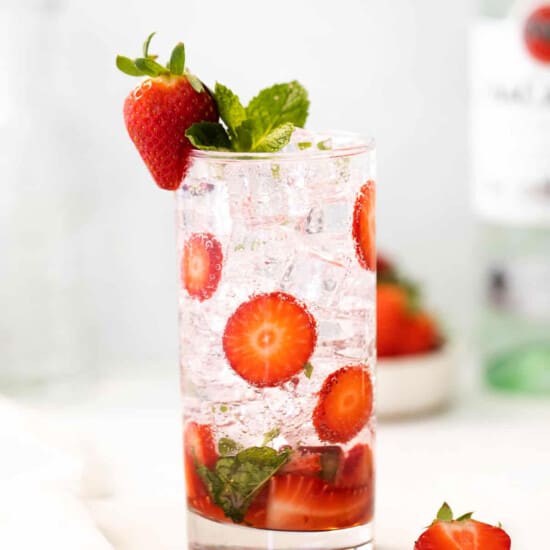 a glass of strawberry gin and tonic with mint leaves.