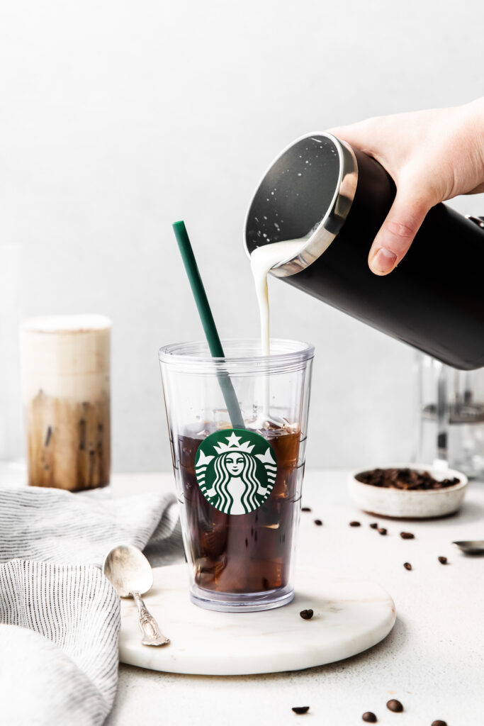 Pouring sweet cream into a glass of cold brew. 