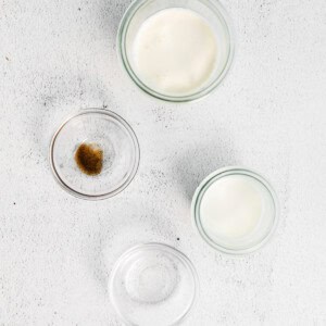 three glass bowls with milk, sugar, and butter on a white background.