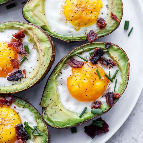 avocados with eggs and bacon on a plate.