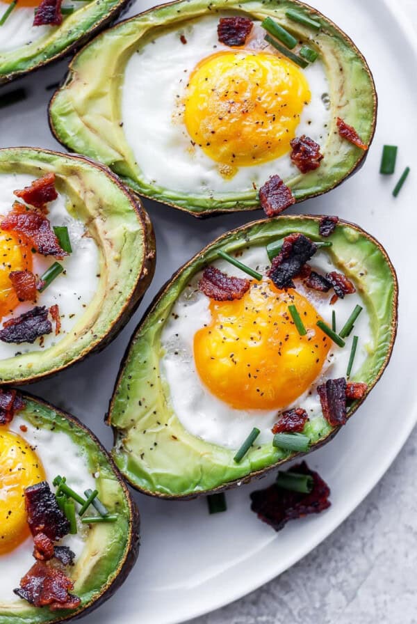 avocados with eggs and bacon on a plate.