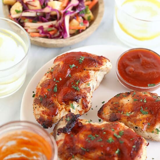 bbq chicken breasts on a plate with coleslaw and ketchup.