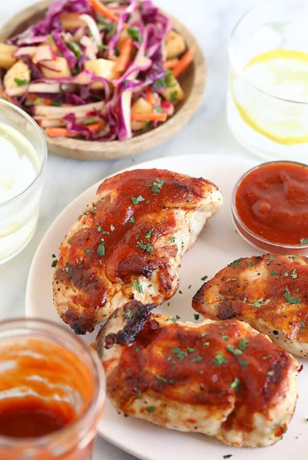 bbq chicken breasts on a plate with coleslaw and ketchup.