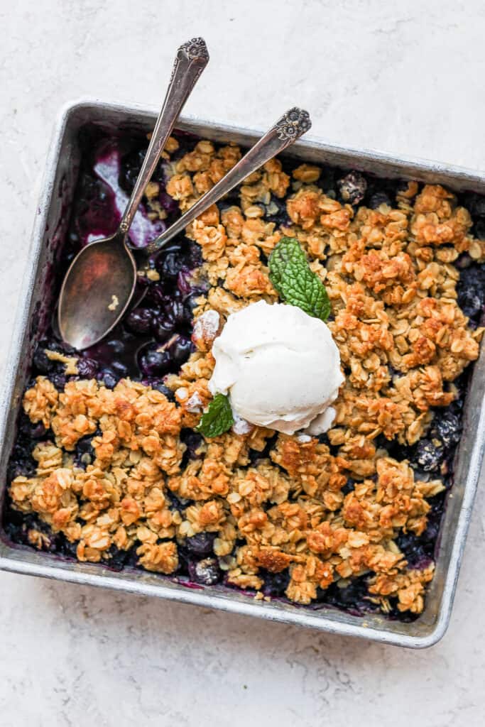 Blueberry crisp in a pan with two spoons. 