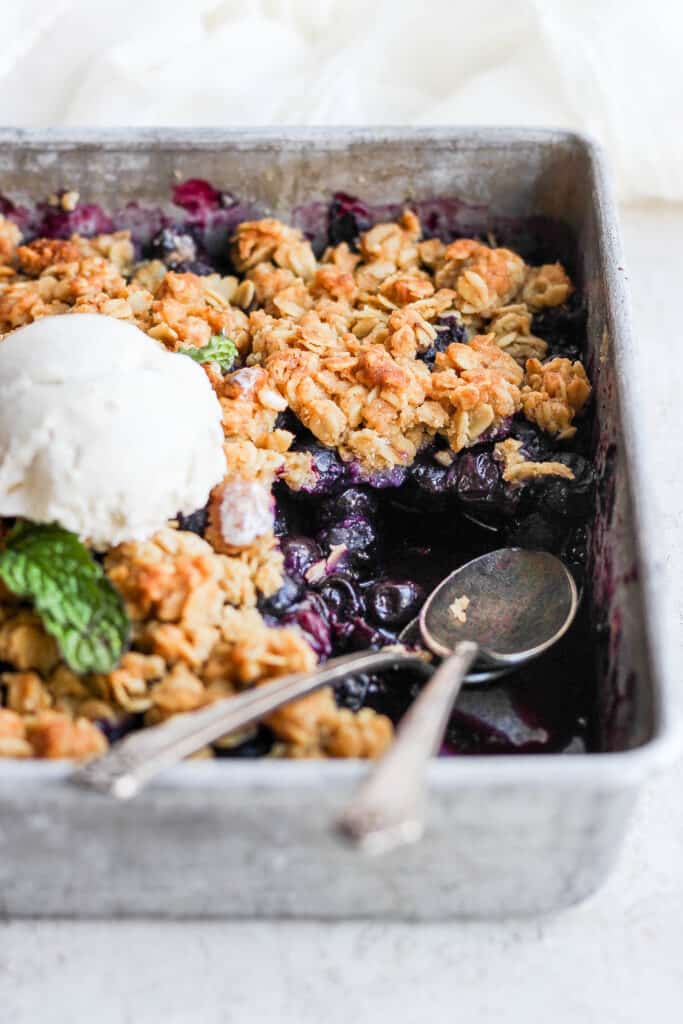 Blueberry crisp in a baking dish with a thick blueberry filling and a golden oat topping. 