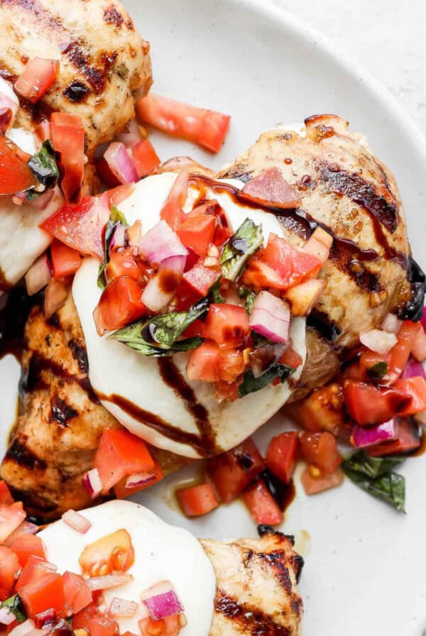 a white plate topped with grilled chicken and veggies.