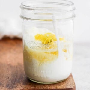 a jar of lemon yogurt on a cutting board.