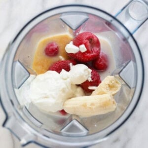 a blender filled with bananas, raspberries and whipped cream.