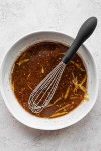 a bowl of chili sauce with a whisk in it.