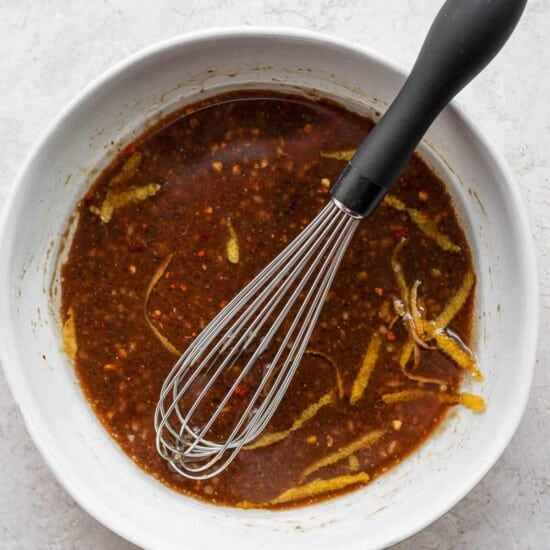 a bowl of chili sauce with a whisk in it.