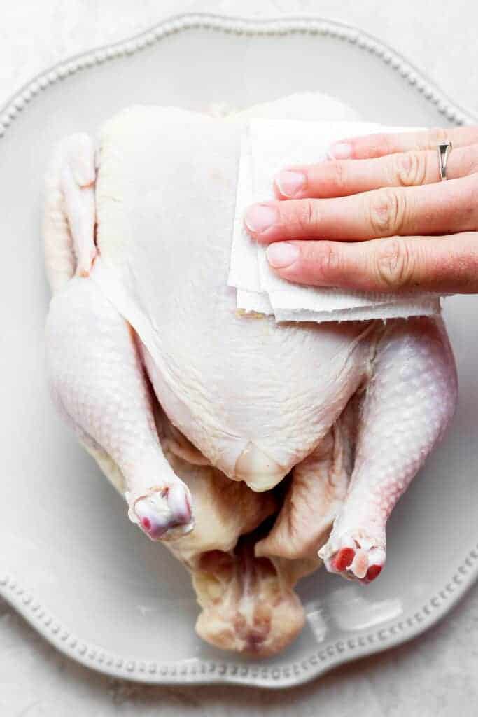 Patting chicken skin dry with a paper towel. 