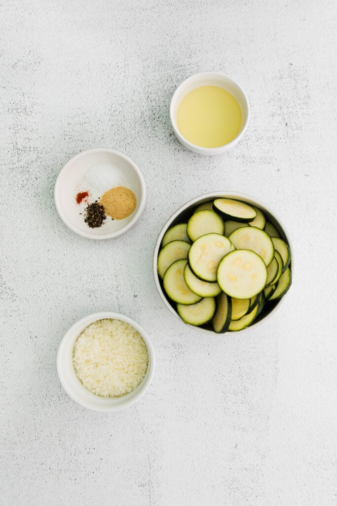All the ingredients for baked zucchini in small bowls. 