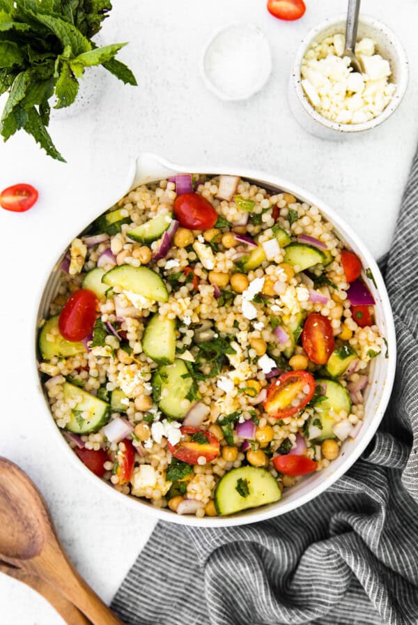 Greek couscous salad in a white bowl.