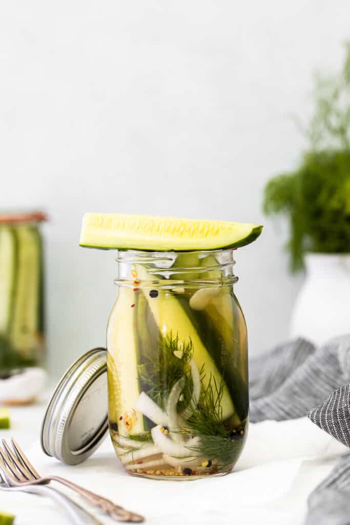 A refrigerator pickle sitting on top of a jar. 