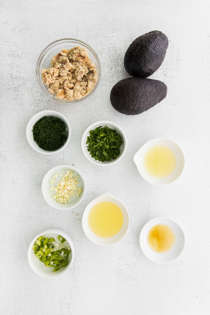 All the ingredients for stuffed avocado boats in small bowls. 