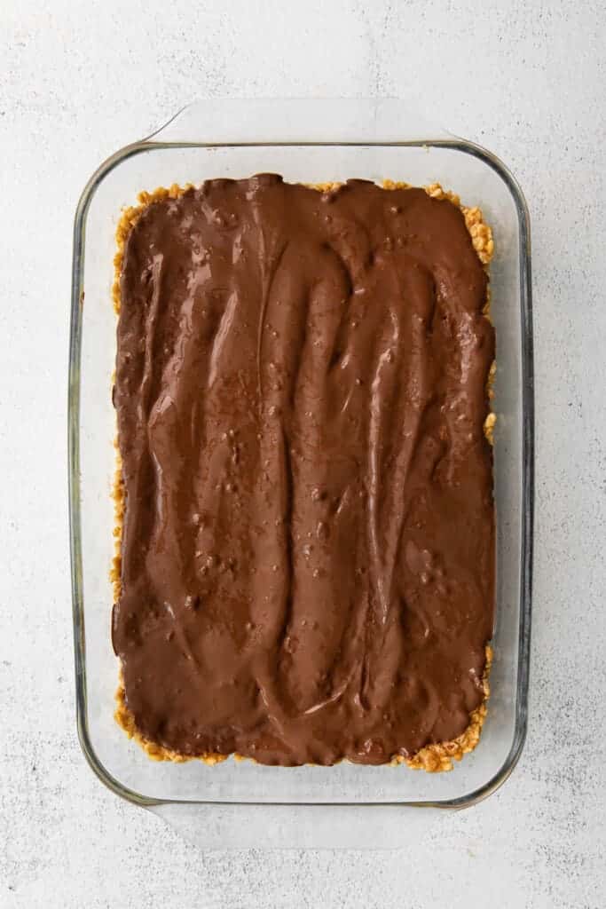 Melted chocolate layer of healthy Scotcheroos in a casserole dish