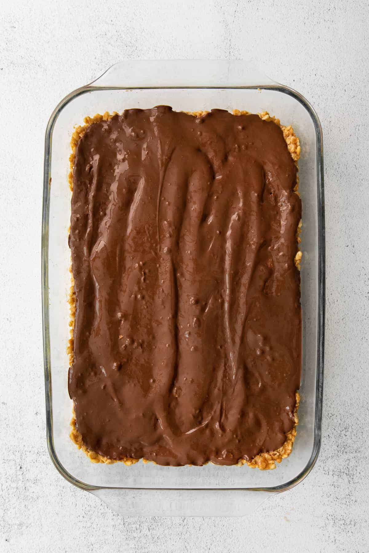 melted chocolate layer of healthy scotcheroos in a baking dish