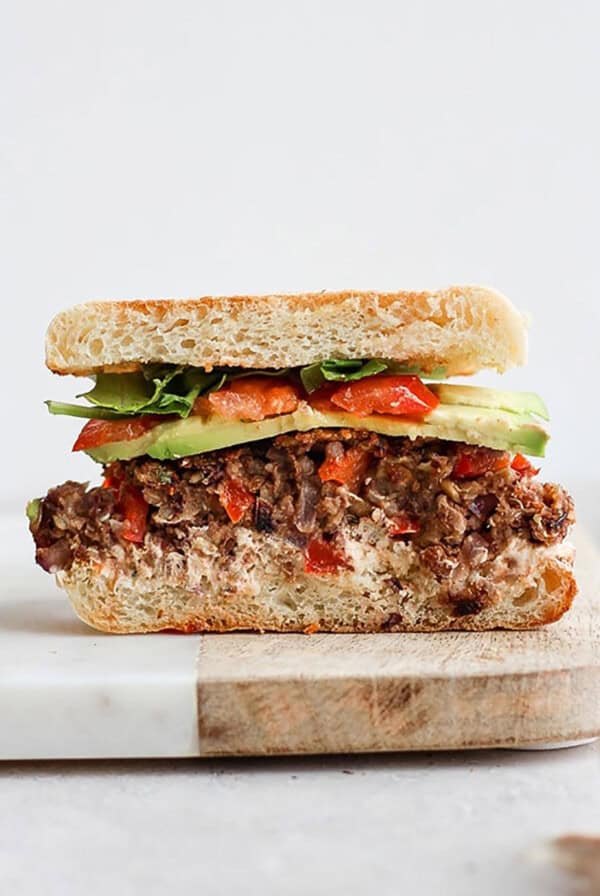 a sandwich with meat and vegetables on a cutting board.