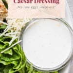 Caesar dressing in a bowl on the side of a salad.