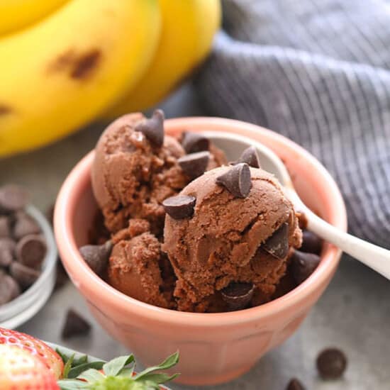a bowl of chocolate ice cream with strawberries and bananas.