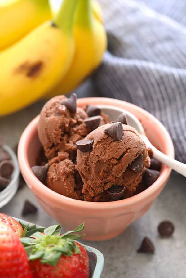 a bowl of chocolate ice cream with strawberries and bananas.