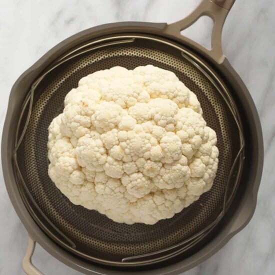 a head of cauliflower in a strainer.