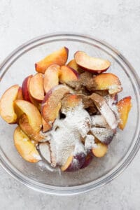 Peach crisp topped with sliced peaches and powdered sugar.