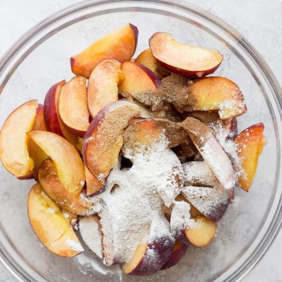 Peach crisp topped with sliced peaches and powdered sugar.
