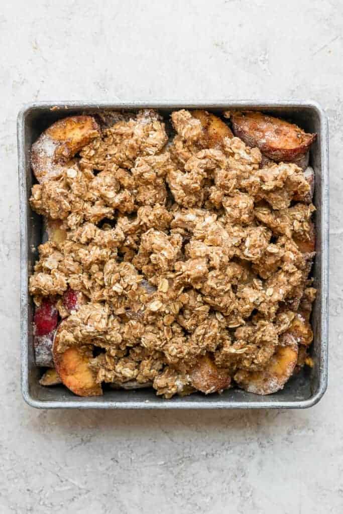 Peach crisp with c،ble topping ready to be baked.