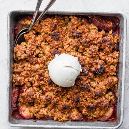 A peach crisp dessert topped with a scoop of ice cream.