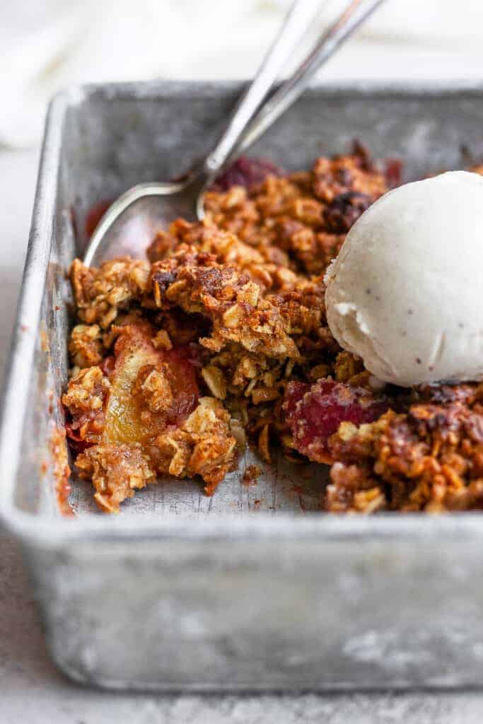 close up of a peach crisp with a scoop of vanilla ice cream