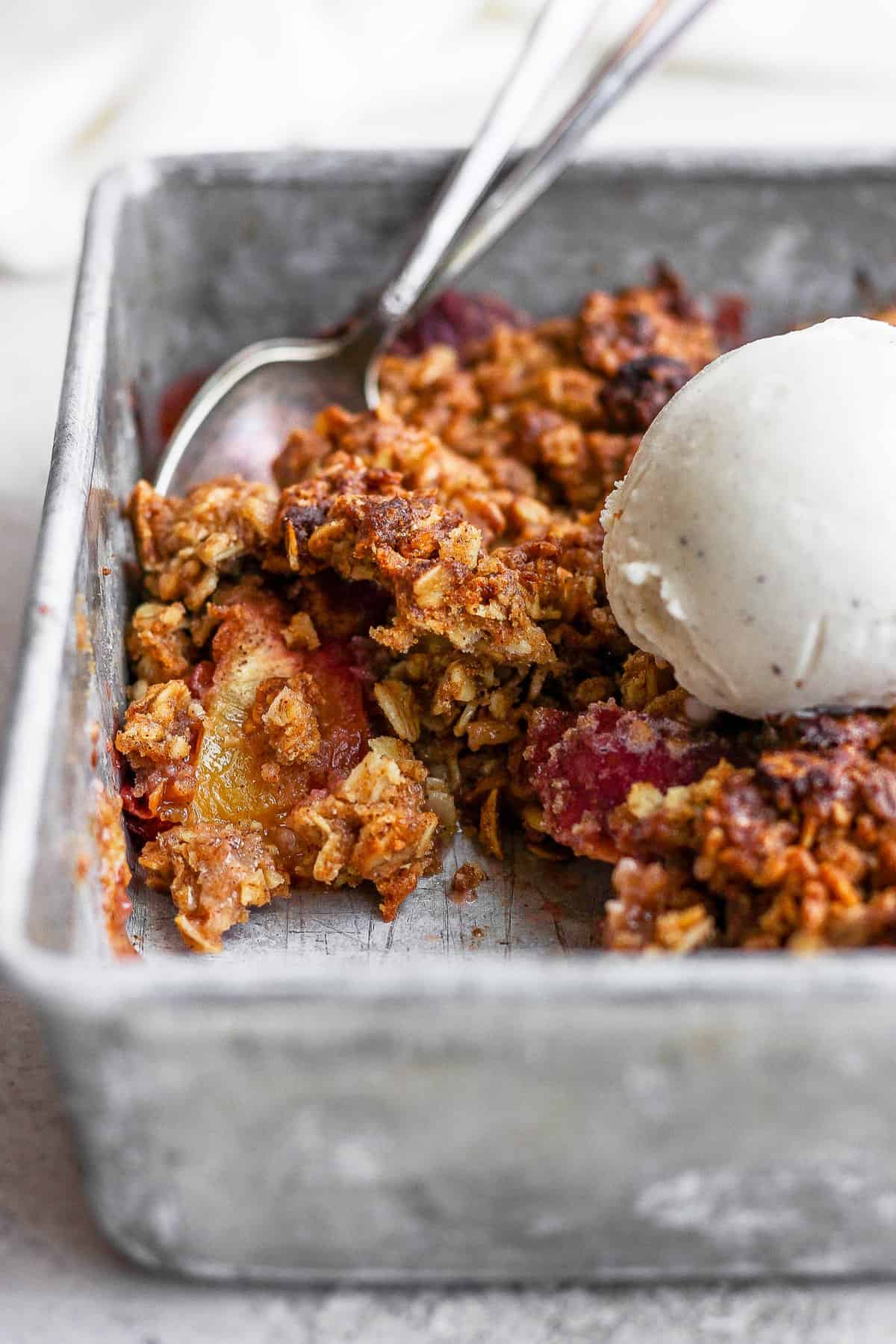 close up of a peach crisp with a scoop of vanilla ice cream