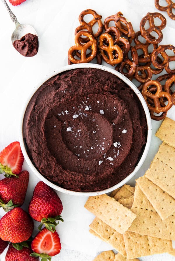a bowl of edible chocolate hummus with strawberries and pretzels.