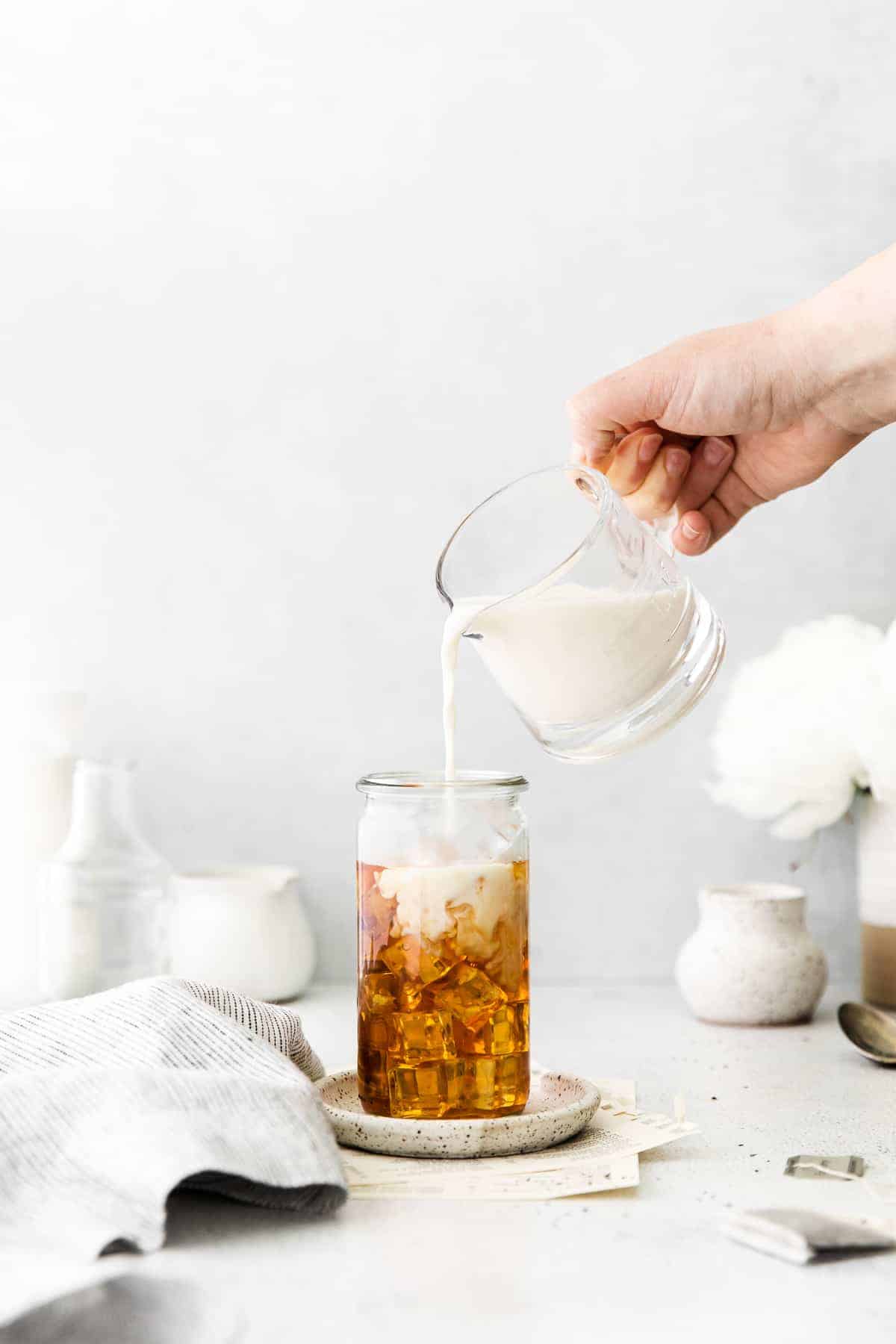 pouring milk on top of iced tea