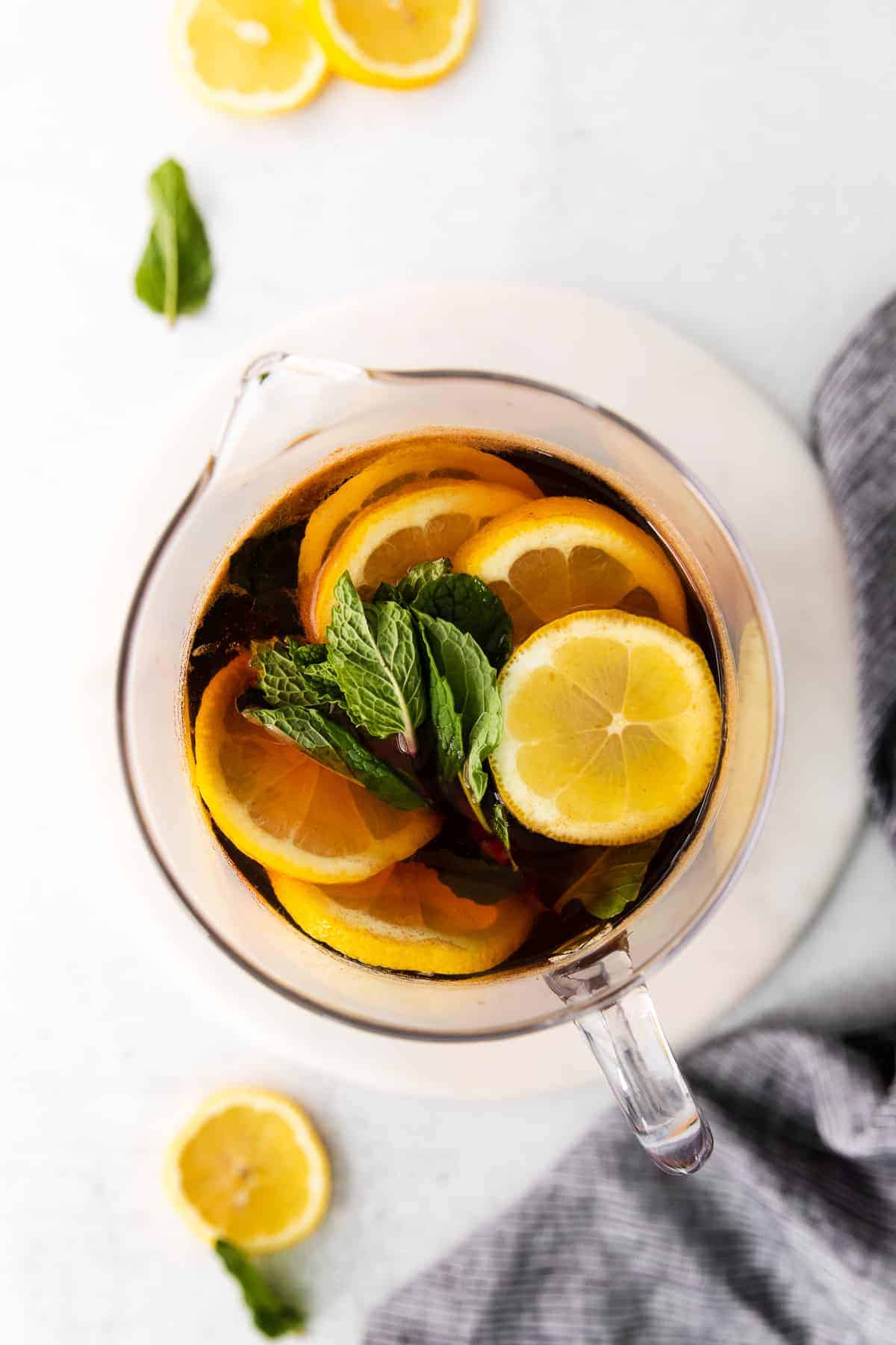 pitcher of iced tea garnished with fresh lemons and mint