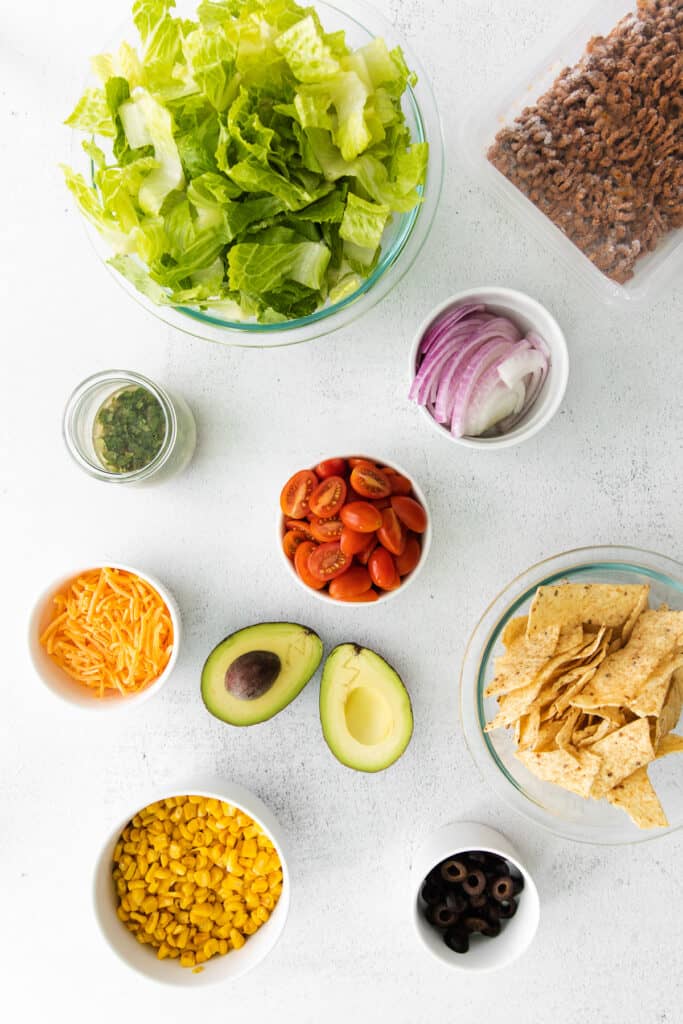 taco salad ingredients in bowls, ready to be combined