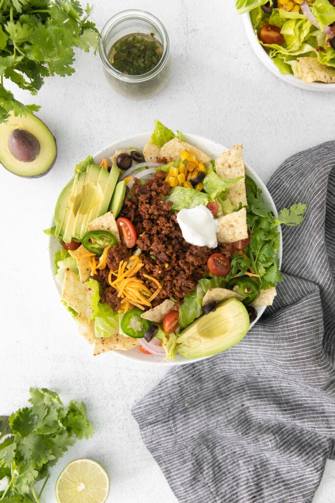 taco salad in a bowl topped with a dollop of greek yogurt and shredded cheese