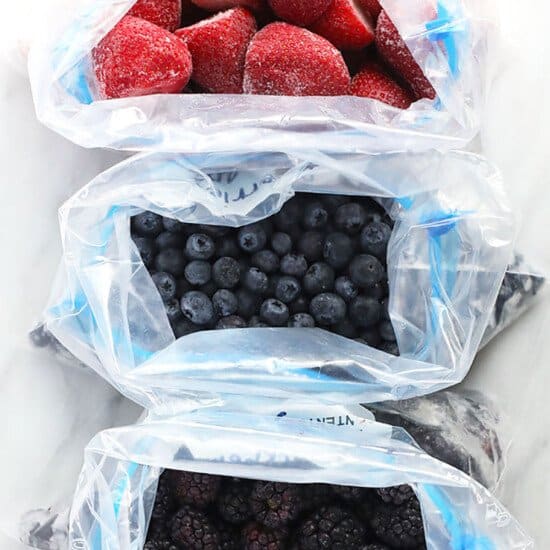 three plastic bags filled with berries and blueberries.