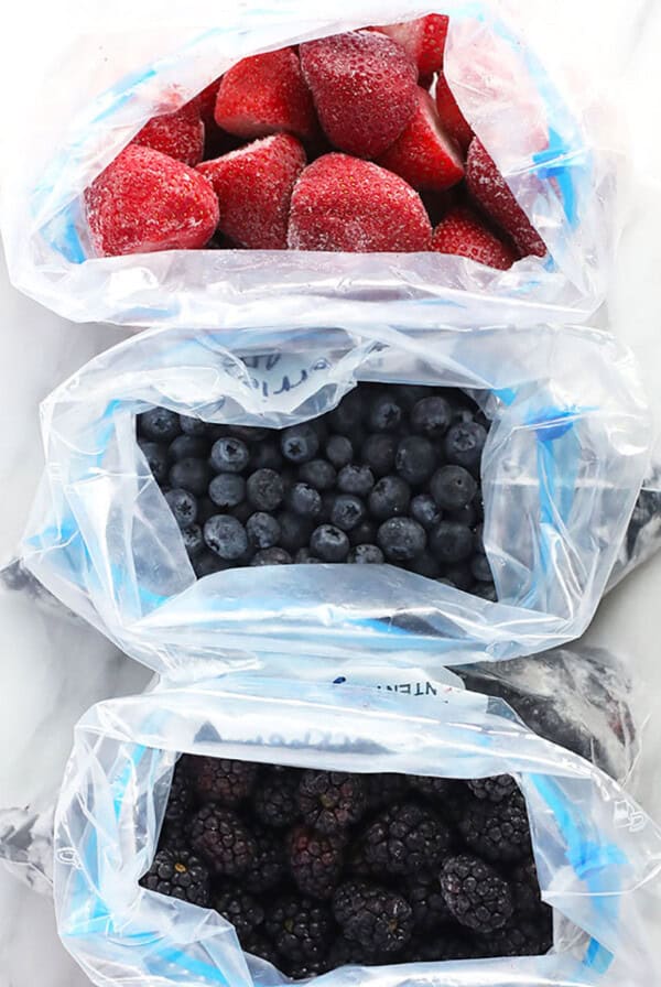 three plastic bags filled with berries and blueberries.