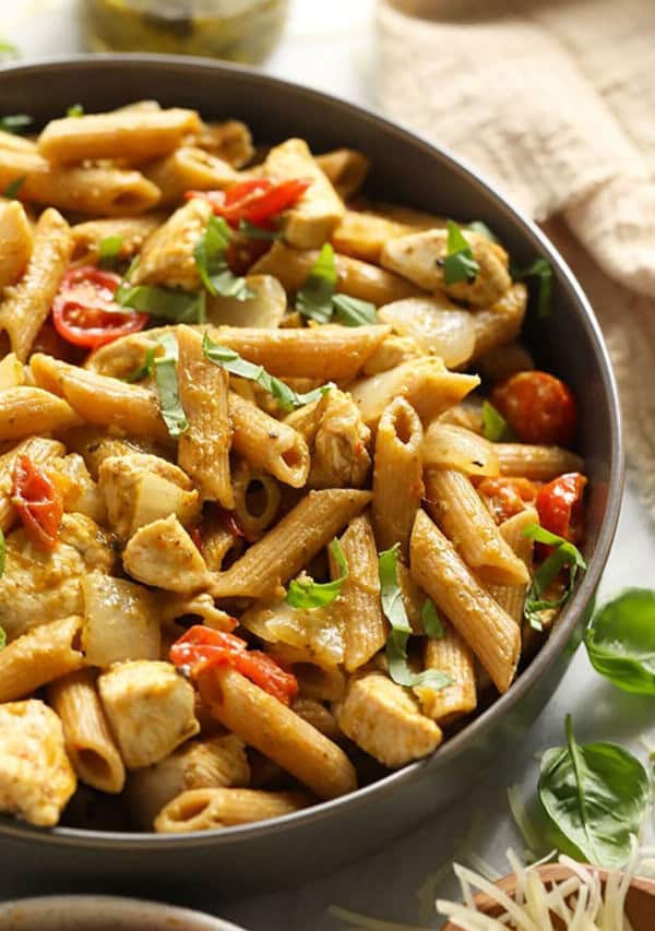 A bowl of pasta with chicken and tomatoes.