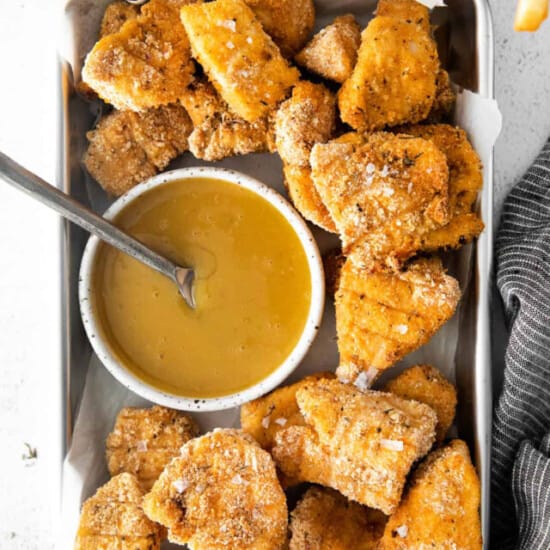 Fried chicken nuggets in a tray with dipping sauce.